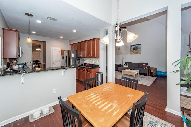 dining area with sink, dark hardwood / wood-style floors, and an inviting chandelier