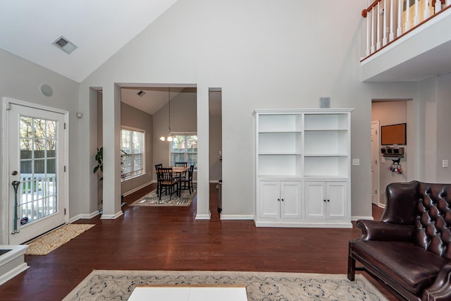 living room featuring high vaulted ceiling, dark wood-type flooring, and a notable chandelier