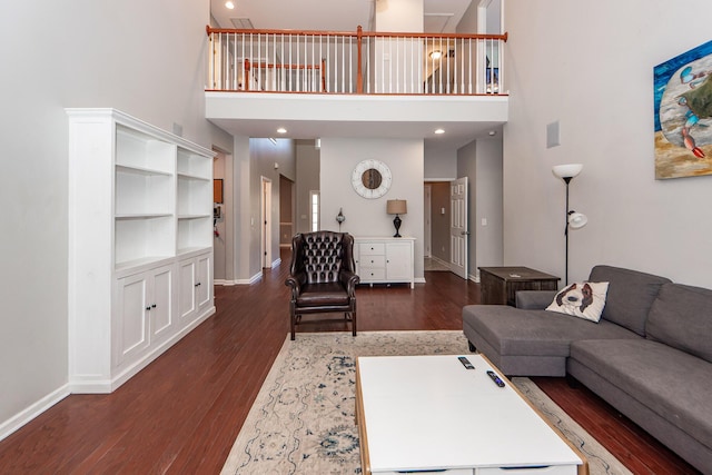 living room with a towering ceiling and dark hardwood / wood-style floors