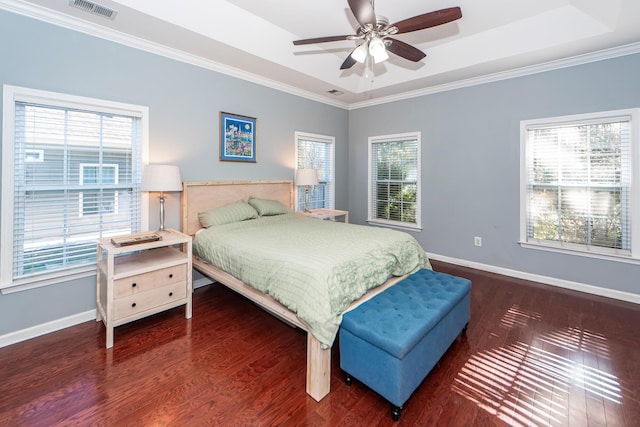 bedroom with multiple windows, dark hardwood / wood-style flooring, a tray ceiling, and ceiling fan