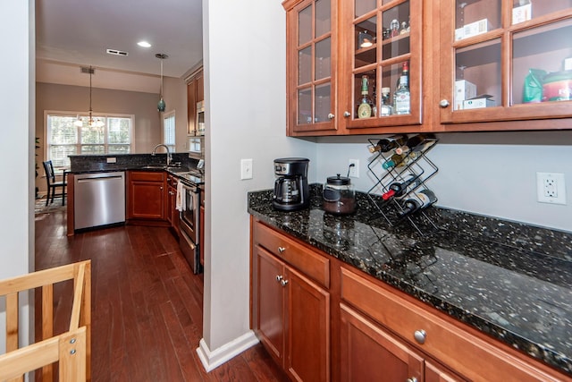 kitchen featuring sink, stainless steel appliances, dark hardwood / wood-style floors, dark stone countertops, and decorative light fixtures