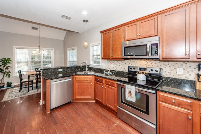 kitchen with a chandelier, stainless steel appliances, hanging light fixtures, and dark stone countertops