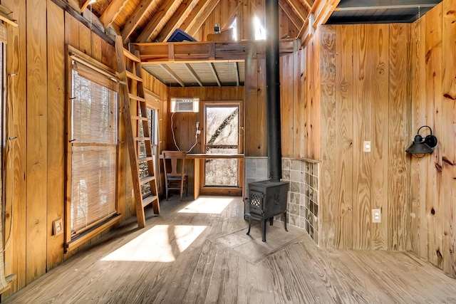 miscellaneous room with wood ceiling, lofted ceiling with beams, a wood stove, and wooden walls