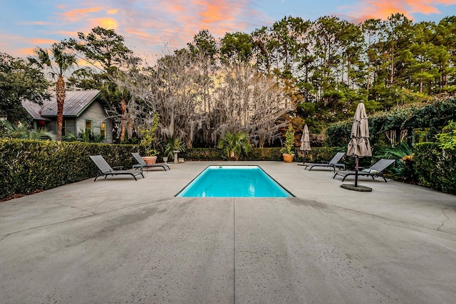 pool at dusk with a patio area