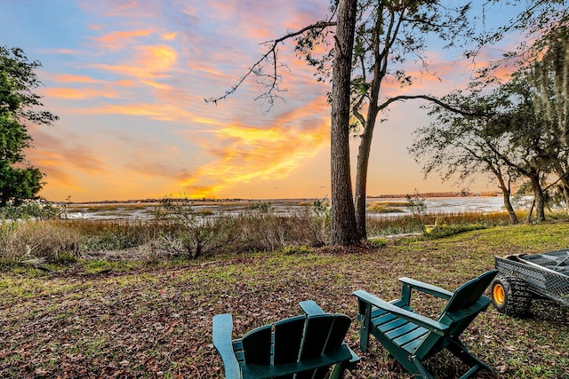 yard at dusk featuring a water view