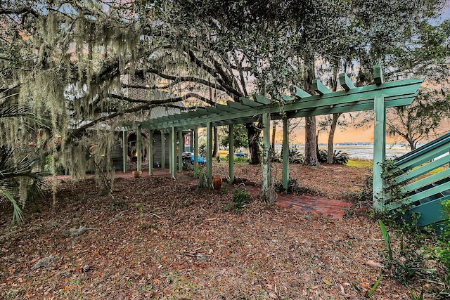 yard at dusk featuring a pergola and a water view