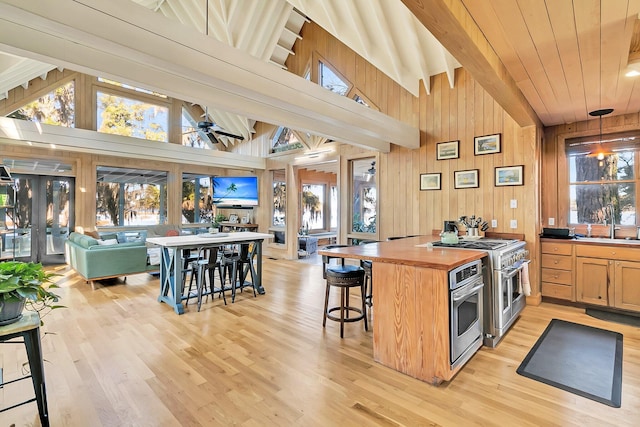 kitchen featuring ceiling fan, a breakfast bar area, appliances with stainless steel finishes, and light hardwood / wood-style flooring