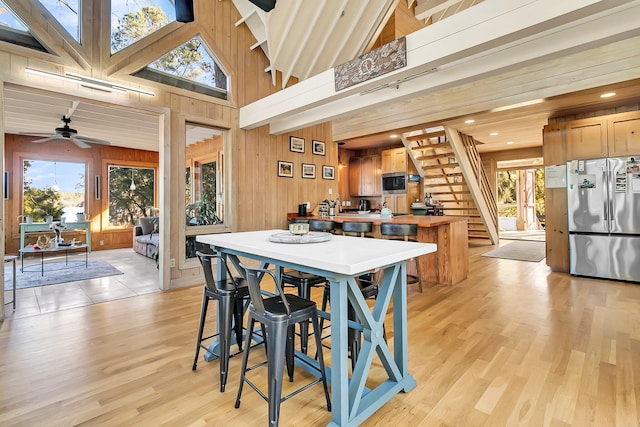 kitchen with wooden walls, ceiling fan, light wood-type flooring, and appliances with stainless steel finishes