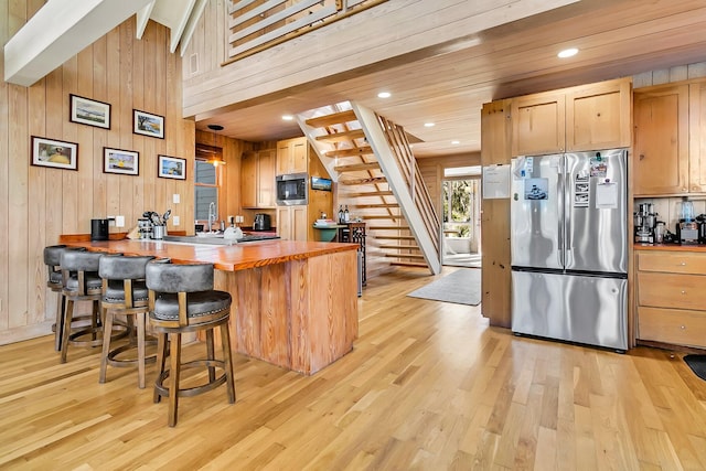 kitchen with wooden walls, a breakfast bar, and appliances with stainless steel finishes