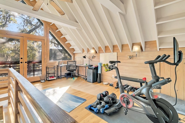 workout room featuring hardwood / wood-style floors, wood walls, french doors, and vaulted ceiling