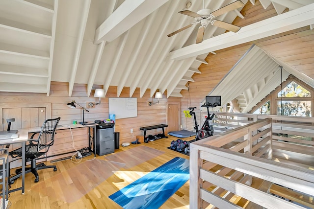 interior space featuring light wood-type flooring, vaulted ceiling, ceiling fan, and wood walls