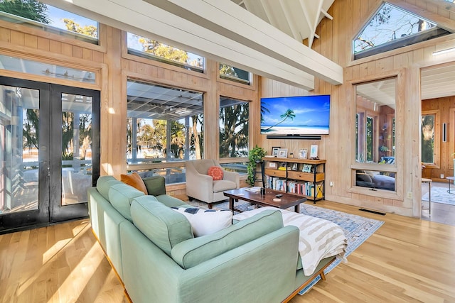 living room featuring hardwood / wood-style flooring, high vaulted ceiling, and wooden walls