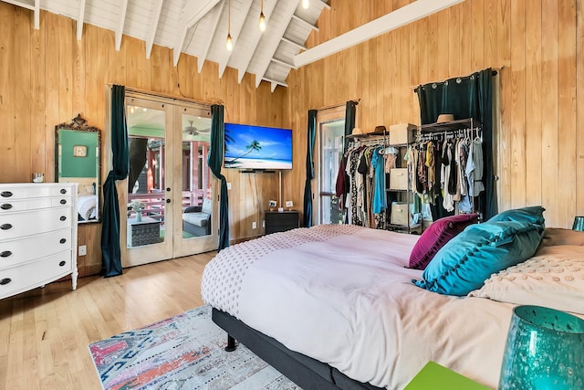 bedroom featuring wood walls, french doors, and lofted ceiling with beams