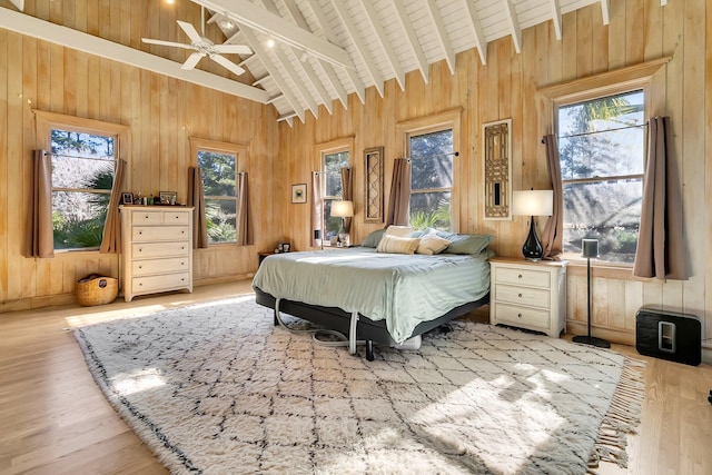 bedroom featuring wood walls, wooden ceiling, high vaulted ceiling, ceiling fan, and beamed ceiling