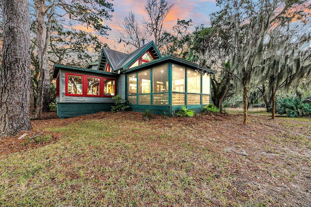 back house at dusk featuring a sunroom