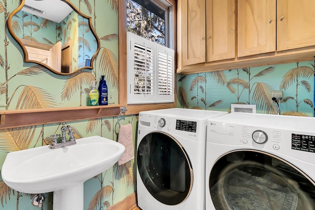 clothes washing area with cabinets, washing machine and dryer, and sink