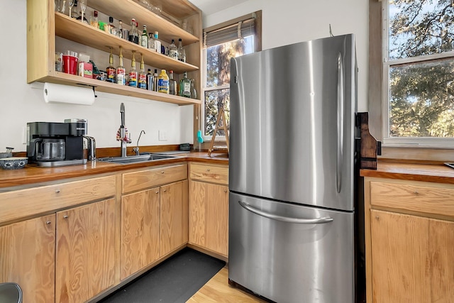 kitchen featuring butcher block countertops, plenty of natural light, sink, and stainless steel refrigerator