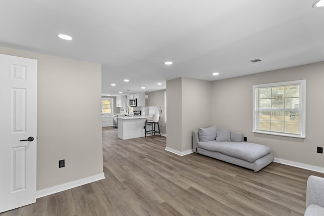 living area with recessed lighting, light wood-style flooring, and baseboards