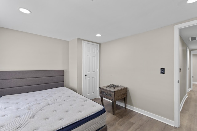 bedroom with recessed lighting, wood finished floors, visible vents, and baseboards