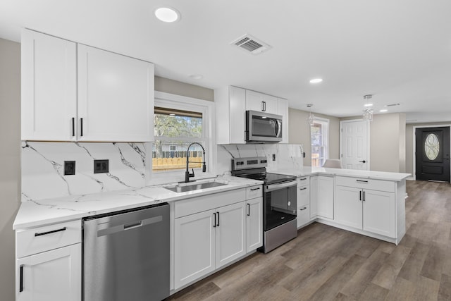 kitchen featuring visible vents, white cabinets, appliances with stainless steel finishes, a peninsula, and a sink