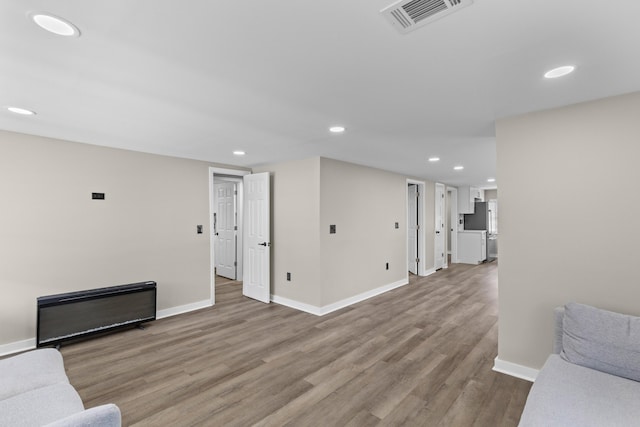 unfurnished living room with baseboards, visible vents, and wood finished floors