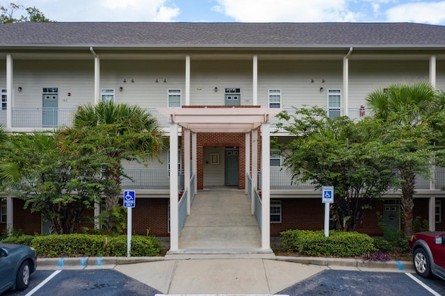 view of exterior entry with uncovered parking and brick siding