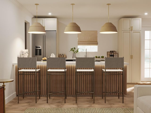 kitchen with white cabinets, crown molding, light wood-type flooring, and high end refrigerator