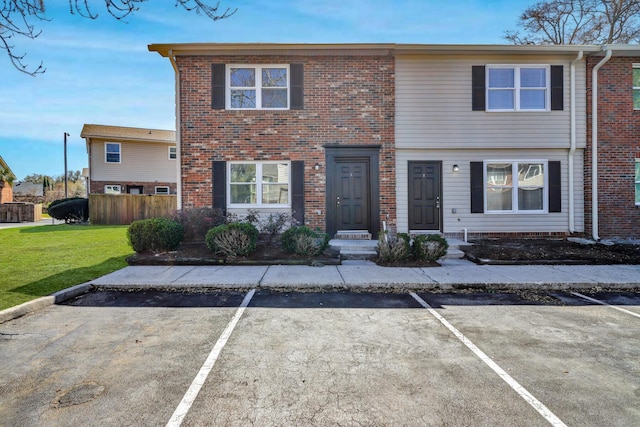 multi unit property with brick siding, a front yard, and fence