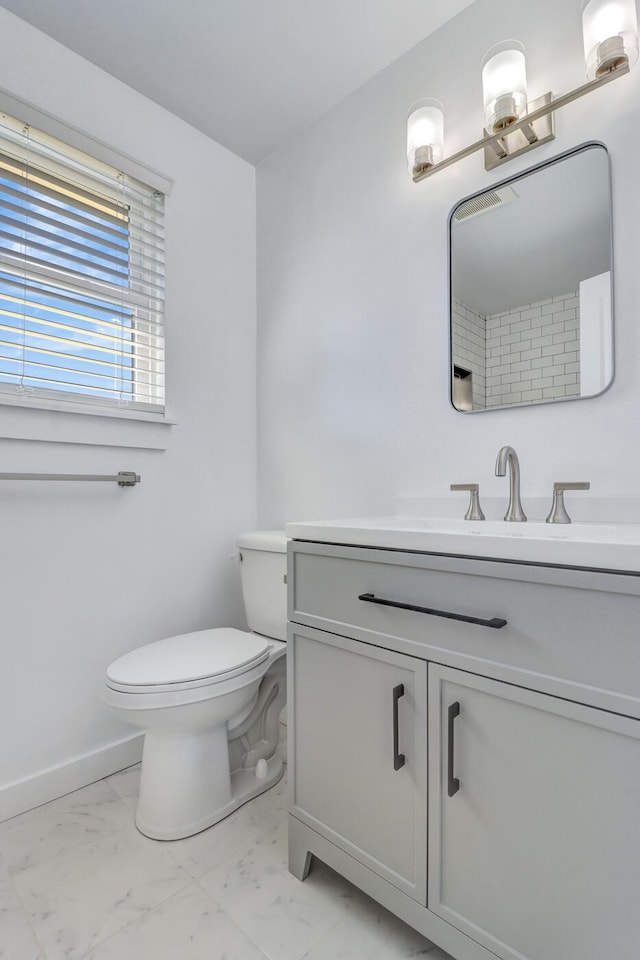 bathroom with vanity, toilet, baseboards, and marble finish floor