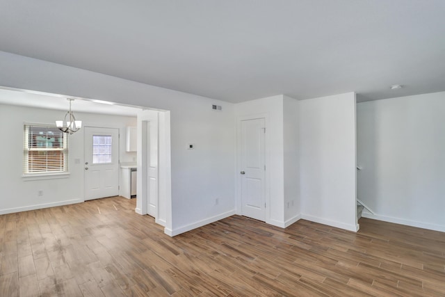 unfurnished room with a notable chandelier, visible vents, baseboards, and wood finished floors