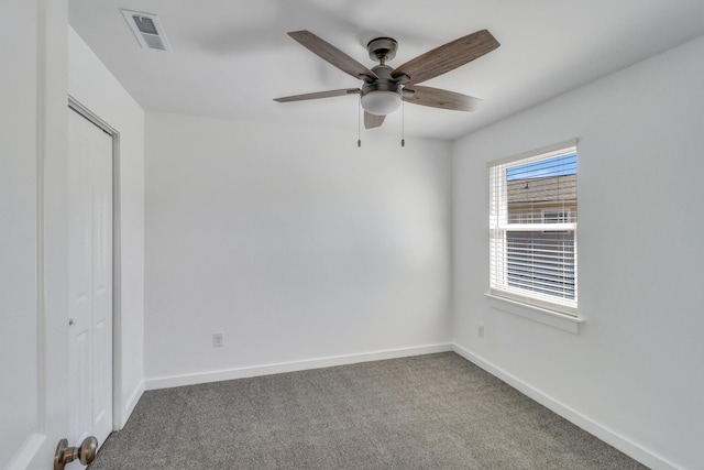 carpeted spare room with visible vents, ceiling fan, and baseboards