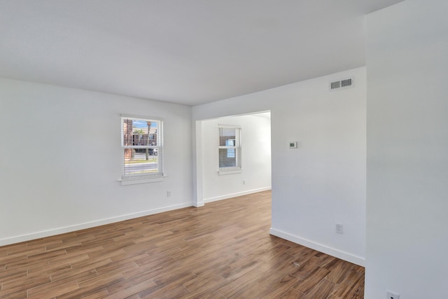 empty room with visible vents, baseboards, and wood finished floors