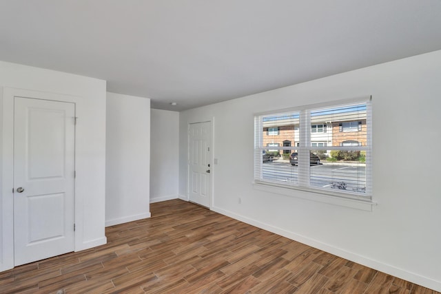 spare room with baseboards and wood finished floors