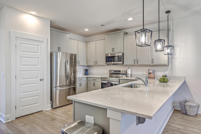 7803 Park Gate Dr, Charleston, SC 29418 - kitchen with a sink, a breakfast bar area, a peninsula, light wood-style flooring, and stainless steel appliances
