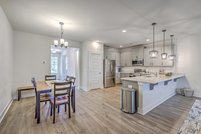 7803 Park Gate Dr, Charleston, SC 29418 - kitchen with light countertops, a peninsula, appliances with stainless steel finishes, light wood-style floors, and a breakfast bar area