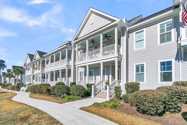 view of property with covered porch, a balcony, and ceiling fan