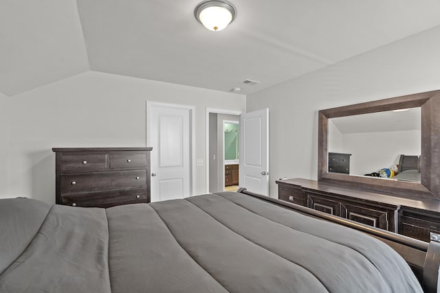 bedroom featuring ensuite bath and vaulted ceiling