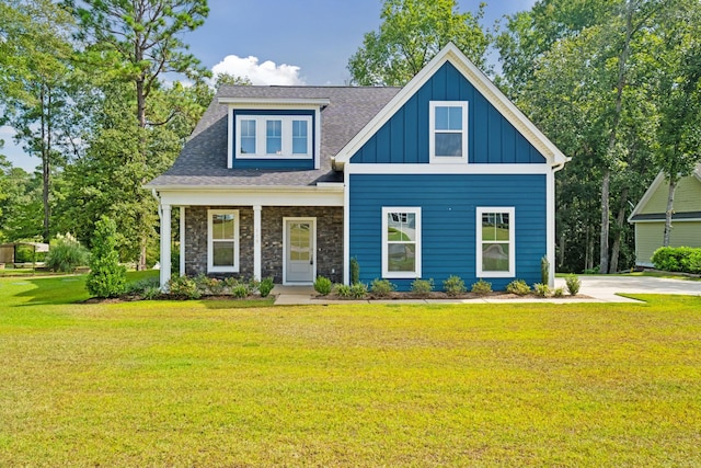 view of front of home featuring stone siding, roof with shingles, board and batten siding, and a front yard