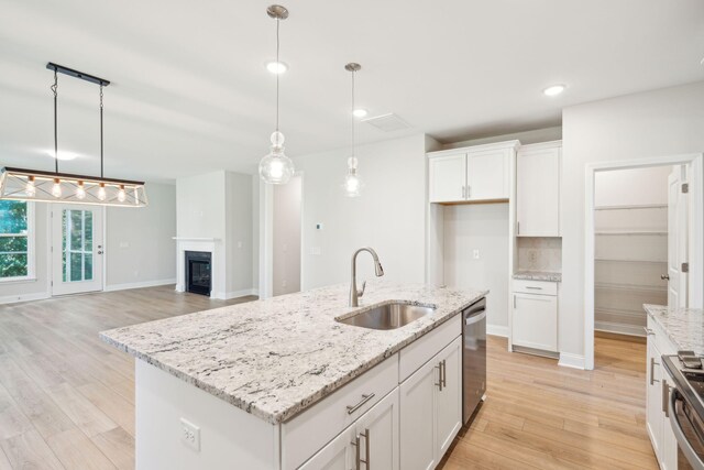 kitchen featuring white cabinets, light hardwood / wood-style floors, a center island with sink, and sink