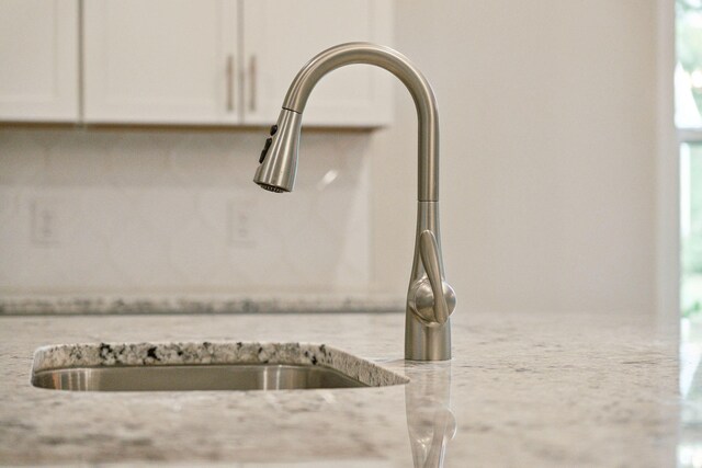 details with white cabinets, sink, and light stone counters