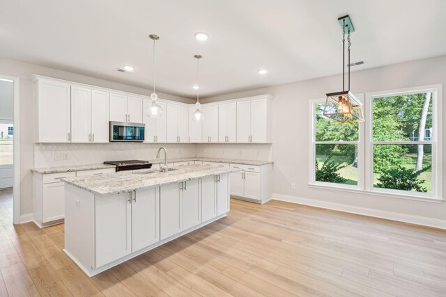 kitchen with white cabinetry, sink, a center island with sink, and light hardwood / wood-style flooring