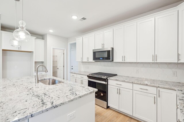 kitchen featuring light hardwood / wood-style floors, stainless steel appliances, hanging light fixtures, sink, and white cabinetry