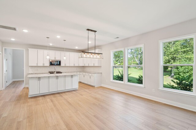 kitchen featuring white cabinetry, plenty of natural light, and decorative light fixtures