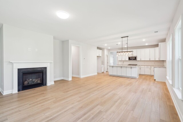 unfurnished living room with a healthy amount of sunlight, sink, and light wood-type flooring