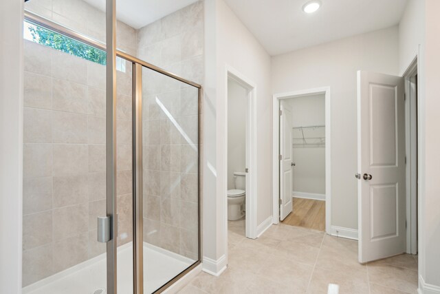 bathroom featuring toilet, tile patterned flooring, and a shower with shower door