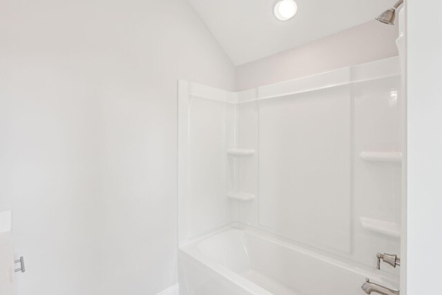 bathroom with washtub / shower combination and lofted ceiling