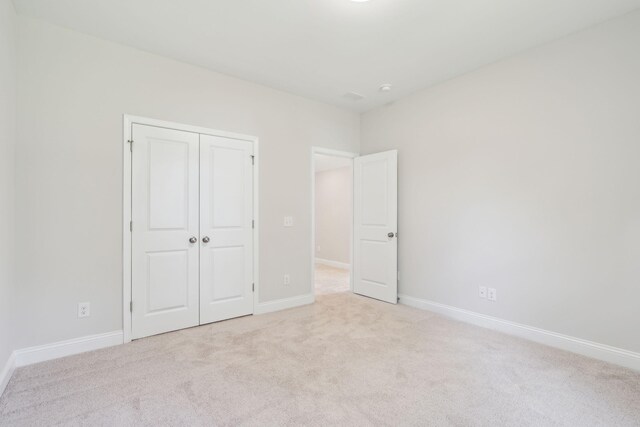 unfurnished bedroom featuring light colored carpet and a closet