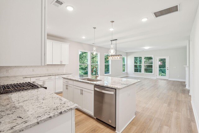 kitchen with stainless steel dishwasher, sink, a center island with sink, and white cabinets