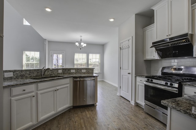 kitchen with a sink, stainless steel appliances, under cabinet range hood, white cabinetry, and backsplash