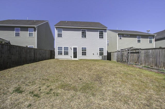 rear view of property featuring a lawn and a fenced backyard